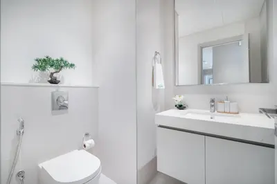a white bathroom with a toilet and a sink at Sunrise Bay with treasure stunning harbour view by Suiteable in Dubai