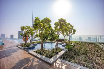 a pool with palm trees on the roof of a building at Elegant apartment in Paramount Midtown residence in Dubai