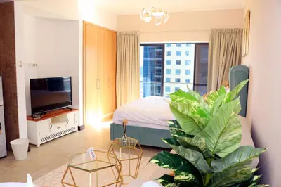 a bedroom with a bed and a tv and a plant at Cosmos Living Spacious with Balcony GCV1 in Dubai