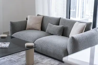 a gray couch sitting in a living room with a table at Canal front apartment with Burj Khalifa view by Suiteable in Dubai