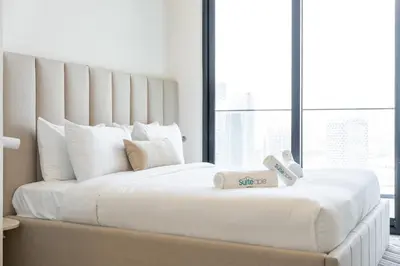 a bedroom with a large white bed with a large window at Canal front apartment with Burj Khalifa view by Suiteable in Dubai