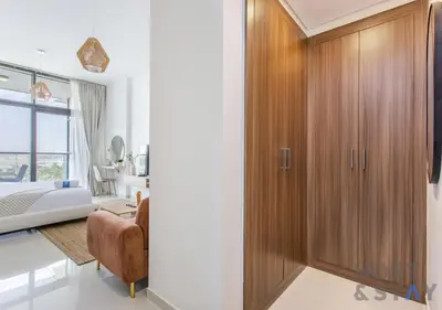 a bedroom with a large wooden closet and a bed at Studio in Jasmine, Damac Hills - Host & Stay in Dubai