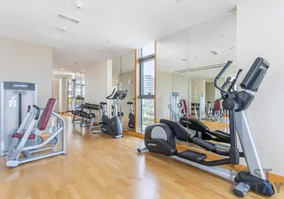 a gym with several treadmills and elliptical machines at Studio in Jasmine, Damac Hills - Host & Stay in Dubai