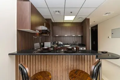 a kitchen with wooden cabinets and a counter with chairs at Special Rates - Elegant Studio - Golf Views in Dubai