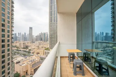 a balcony with tables and chairs and a view of a city at RH- Studio Retreat, Walk away to Burj Khalifa and Dubai Mall in Dubai