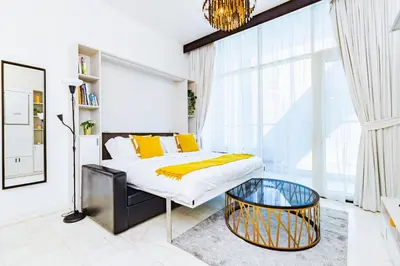 a bedroom with a bed and a glass table at Waves Holiday Homes - Chic Studio With Balcony Overlooking City Views in Dubai
