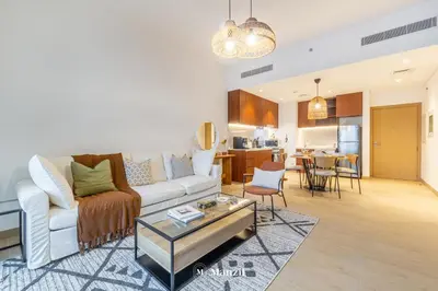 a living room with a white couch and a table at Manzil - 1BR Home in Port de la Mer w Lake Access in Dubai