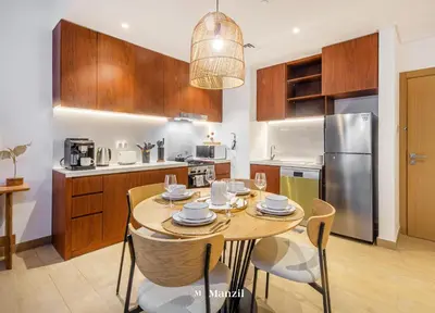 a kitchen with a wooden table with chairs and a dining room at Manzil - 1BR Home in Port de la Mer w Lake Access in Dubai