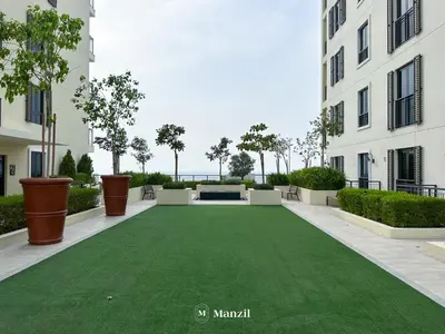 a green lawn in the middle of a building at Manzil - 1BR Home in Port de la Mer w Lake Access in Dubai
