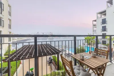 a balcony with a table and a view of the water at Manzil - 1BR Home in Port de la Mer w Lake Access in Dubai