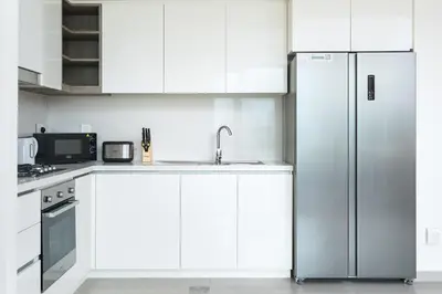 a kitchen with white cabinets and a stainless steel refrigerator at BellaVista Downtown Views II Tower 1 Modern 2BR Downtown City View in Dubai