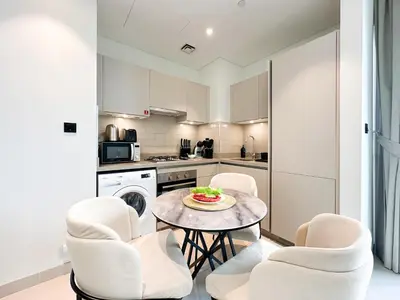 a kitchen with white chairs and a table with a bowl of fruit at Trophy - Maison de Charme Suite in Dubai