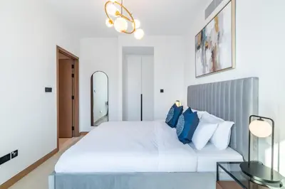 a white bedroom with a large bed with blue pillows at Welcome Home Apartments - VIDA Marina - Full Marina view - High Floor in Dubai