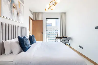a bedroom with a white bed with blue pillows at Welcome Home Apartments - VIDA Marina - Full Marina view - High Floor in Dubai