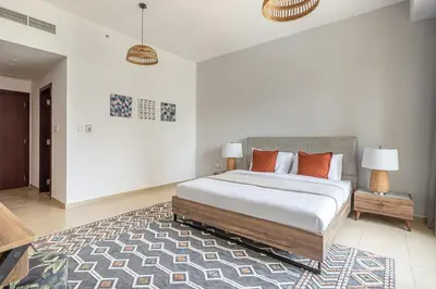 a white bedroom with a large bed with orange pillows at Frank Porter - Bahar 1 in Dubai