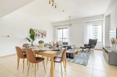 a dining room and living room with a table and chairs at Frank Porter - Bahar 1 in Dubai