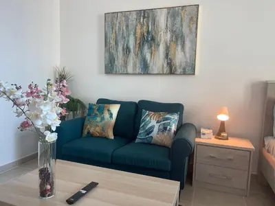 a living room with a blue couch and a table at Studio in Silicon Oasis in Dubai