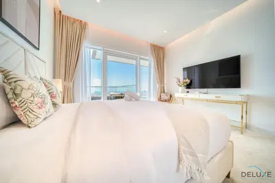a white bedroom with a large bed and a television at Picturesque 3BR with Assistant Room at The One JBR by Deluxe Holiday Homes in Dubai