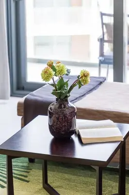 a vase with flowers on a table with a book at Frank Porter - Damac Celestia in Dubai