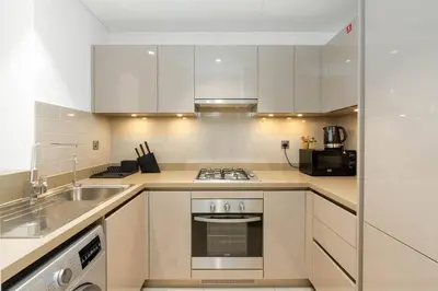 a kitchen with white cabinets and a sink and a stove at Serenity Studio in Dubai