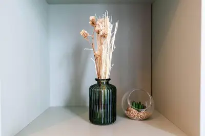a green vase with dried flowers in it on a table at Serenity Studio in Dubai
