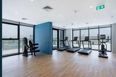 a gym with treadmills and ellipticals in a room with windows at Modern Stu Near Downtown Dubai Pool Gym WiFi in Dubai