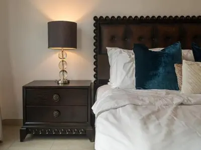 a bedroom with a bed with a night stand with a lamp at Elegant Apartment Overlooking Dubai Mall Fountain. in Dubai
