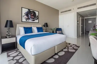 a bedroom with a large bed with blue pillows at Frank Porter - DAMAC Artesia in Dubai