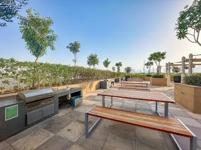 a row of picnic tables with trees in the background at Modern 1BR at Farhad Azizi Al Jaddaf - Sleeps 4 in Dubai