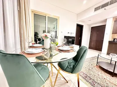 a dining room with a glass table and green chairs at Lovely Newly Furnished Ocean View Studio in Royal Oceanic Tower in Dubai