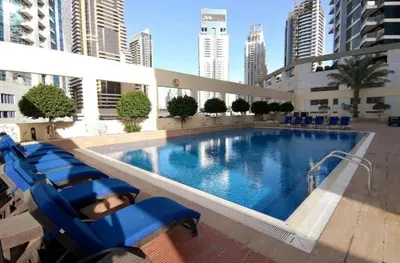 a large swimming pool in a building with blue chairs at Lovely Newly Furnished Ocean View Studio in Royal Oceanic Tower in Dubai