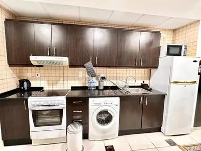 a kitchen with a white refrigerator and a dishwasher at Lovely Newly Furnished Ocean View Studio in Royal Oceanic Tower in Dubai