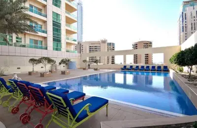a large swimming pool with chairs and a building at Lovely Newly Furnished Ocean View Studio in Royal Oceanic Tower in Dubai