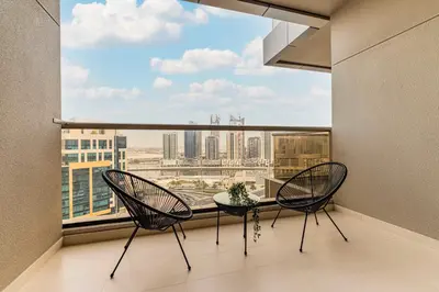 a balcony with two chairs and a table and a large window at Daniels Cityscape Studio at Elite Downtown in Dubai