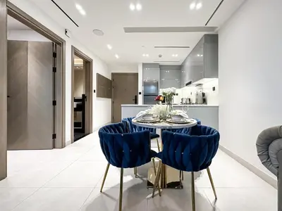 a dining room with a table and blue chairs at Trophy Lux Suite With Garden Balcony and Burj Khalifa Views in Dubai