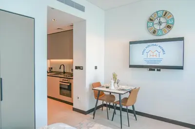 a kitchen with a table and chairs and a clock on the wall at Urban Skyline City Comfort Studio in Dubai
