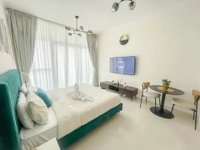 a bedroom with a bed and a table and a tv at Modern Condo With Wide City Views From Balcony in Dubai