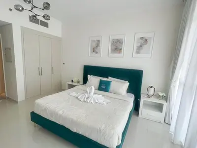 a bedroom with a bed with a green headboard at Modern Condo With Wide City Views From Balcony in Dubai