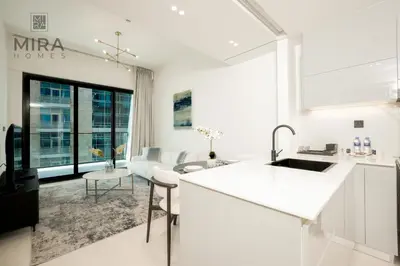 a kitchen with white counters and a living room at Mira Holiday Homes - Serviced 1 bedroom with canal view in Dubai
