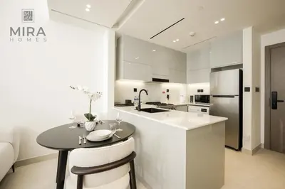 a white kitchen with a table and a counter at Mira Holiday Homes - Serviced 1 bedroom with canal view in Dubai