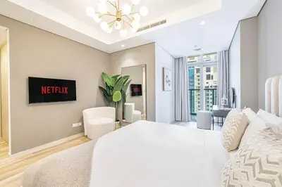 a white bedroom with a bed and a tv at Daniels Burj Khalifa View 2BR at Paramount Midtown in Dubai