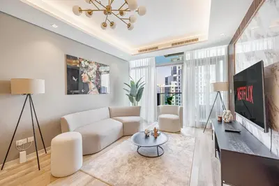 a living room with a couch and a tv at Daniels Burj Khalifa View 2BR at Paramount Midtown in Dubai