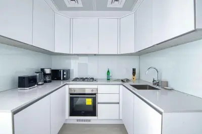 a white kitchen with white cabinets and a sink at The Smart Concierge - Luma 21 in Dubai