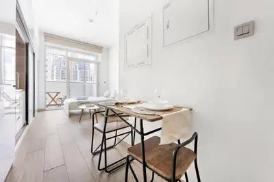 a white living room with a table and chairs at StoneTree - Studio One Tower Studio - Amazing View and Facilities in Dubai