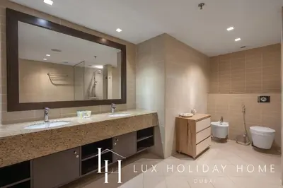 a large bathroom with two sinks and a toilet at LUX The Anantara Residence Suite in Dubai