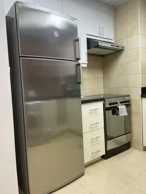 a stainless steel refrigerator in a kitchen next to a stove at Sunset Oasis: Beachfront Studio in Dubai
