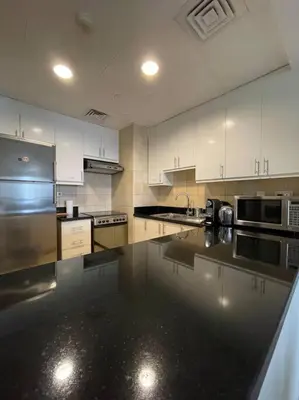 a kitchen with white cabinets and a black counter top at Sunset Oasis: Beachfront Studio in Dubai
