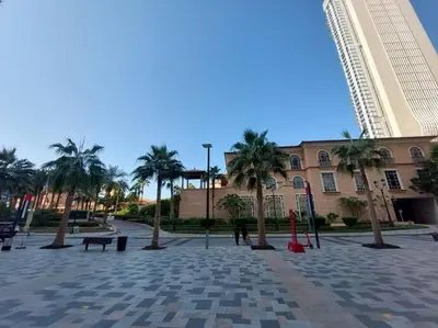 a courtyard with palm trees in front of a building at Sunset Oasis: Beachfront Studio in Dubai