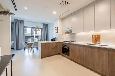 a kitchen with white cabinets and a table with chairs at Spacious 3BDR Townhouse I Garden I Tilal Al ghaf in Dubai