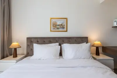 a bedroom with a bed with white sheets and two lamps at Spacious 3BDR Townhouse I Garden I Tilal Al ghaf in Dubai
